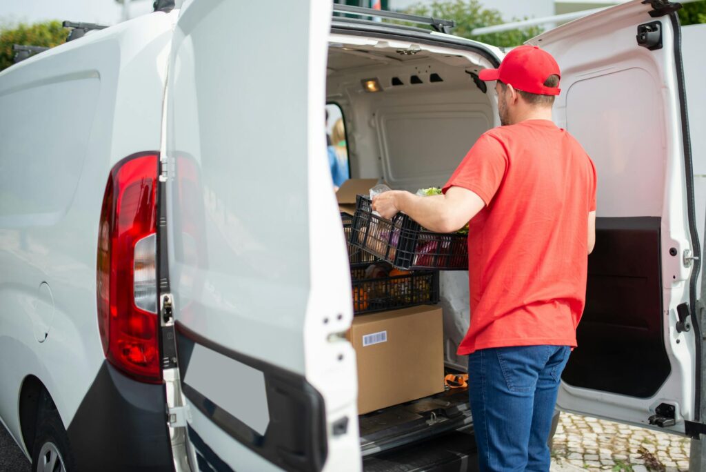 Livreur charge des caisses de légumes dans camionnette
