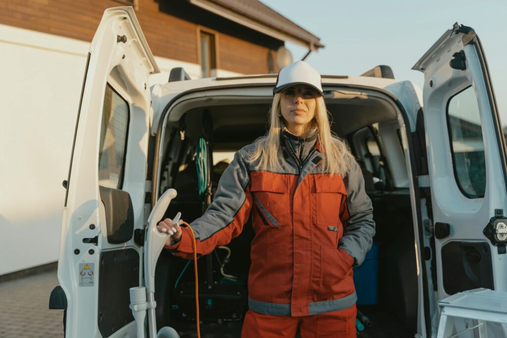 Technicienne en uniforme devant utilitaire portes ouvertes