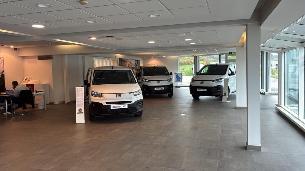 Showroom automobile avec trois utilitaires Fiat blancs