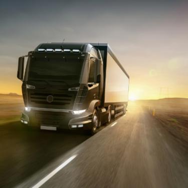 Camion semi-remorque noir roulant au coucher du soleil